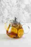 Free photo vertical view of tea time with mixed herbal tea with lemon in a glass pot on white table