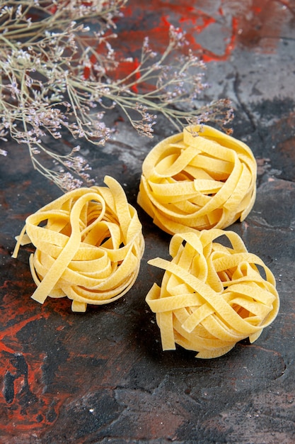 Vertical view of three uncooked spaggeties on mixed color background