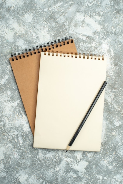 Vertical view of two kraft spiral notebook with pen on ice background