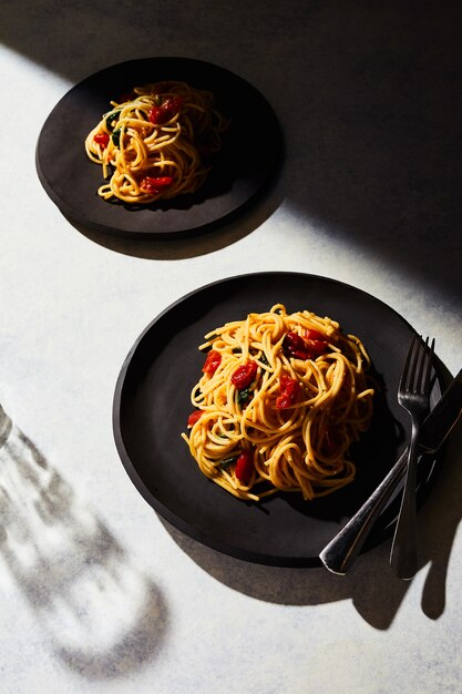 Vertical view of two plates of spaghetti on a white surface