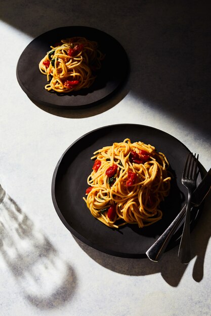 Вертикальный вид двух тарелок спагетти на белой поверхности