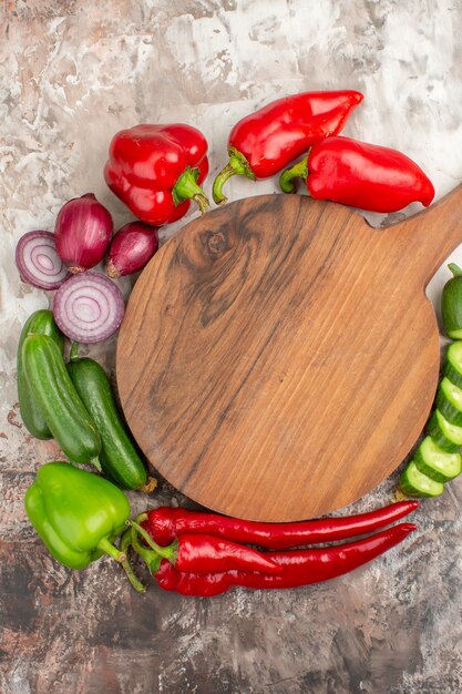 Vertical view of whole and chopped fresh vegetables and wooden cutting board