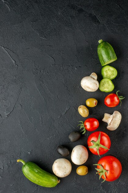 全体の垂直方向のビューと黒い表面に新鮮な野菜の生のキノコをカット