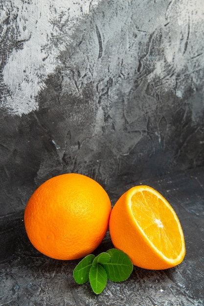 Vertical view of whole and cut in half fresh oranges on gray background