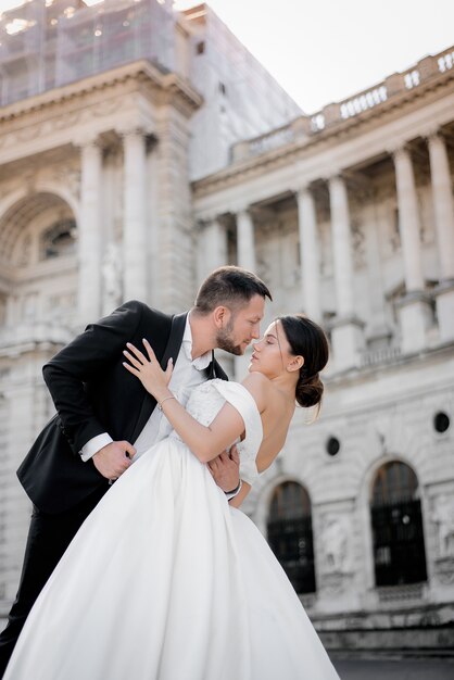 Vertical wedding photo of groom and bride a moment before a kiss in front of historical building