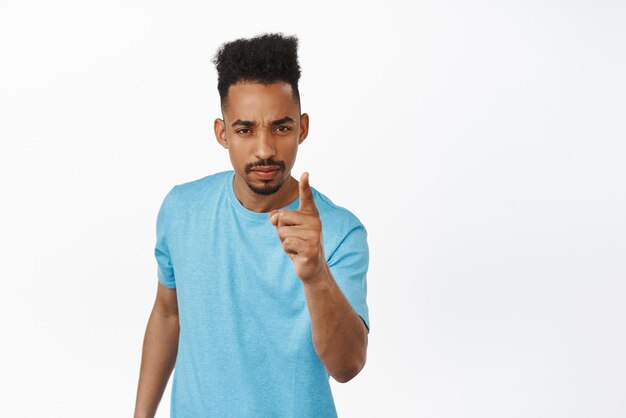 Very bad behaviour Disappointed african american young man scolding person shaking finger furrow eyebrows and squinting displeased teaching lesson warn you white background