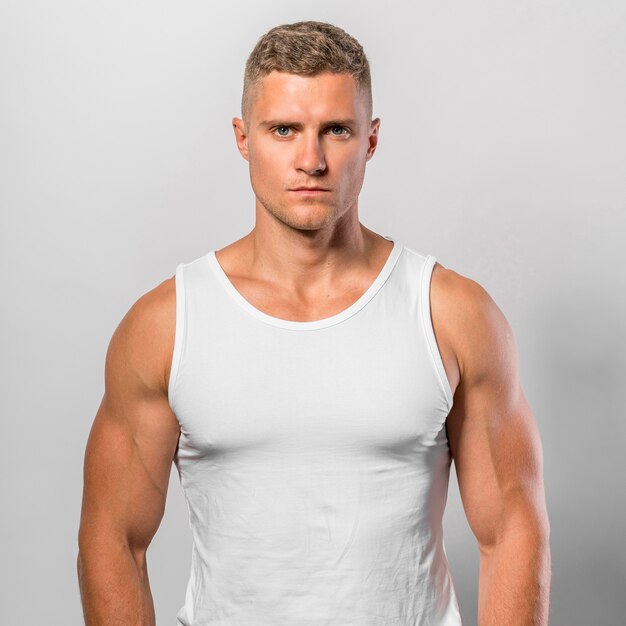 Very fit man posing while wearing tank top