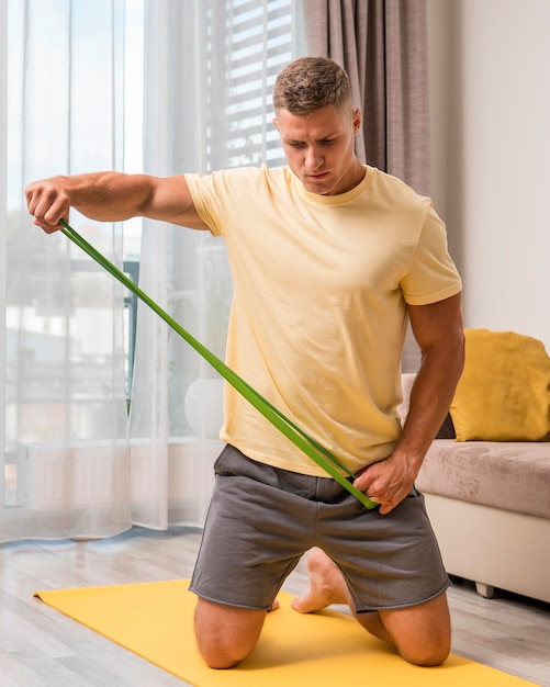 Foto gratuita uomo molto in forma che lavora a casa utilizzando un elastico