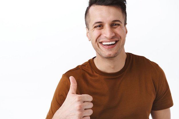 Very good definitely recommend Handsome cheerful smiling adult man give positive reaction to awesome performance show thumbup and laughing approve and like product white background