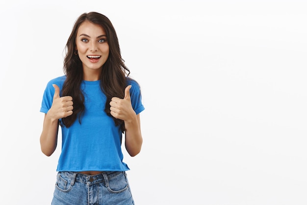 Very good nice idea Upbeat and optimistic smiling brunette girl satisfied after watching awesome comedy show thumbsup in approval like your choice standing white background