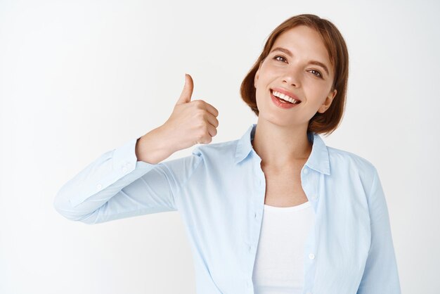 Very good Portrait of businesswoman showing thumb up like and approve say yes and agree standing in blouse on white background