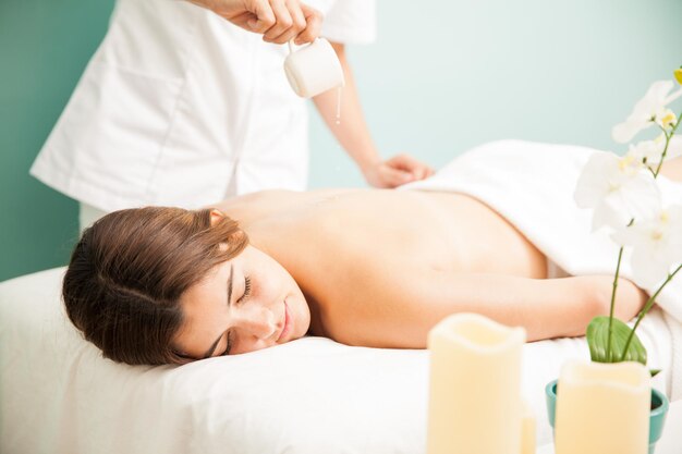 Very relaxed and cute young woman getting a candle massage at a beauty clinic and spa