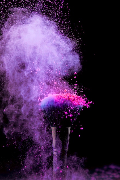 Vibrant burst of makeup powder with brush on dark background