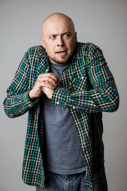 Vicious emotional man in shirt posing over beige wall