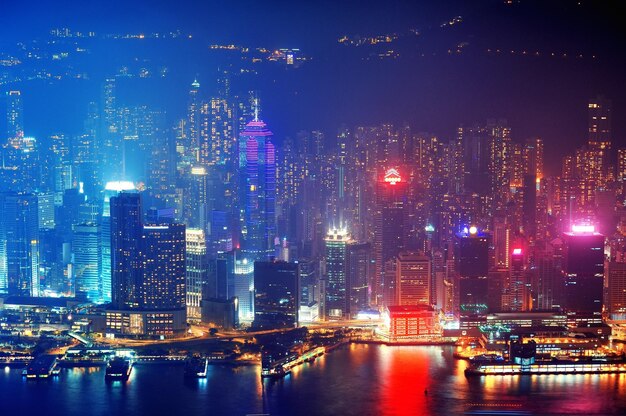 Victoria Harbor aerial view with Hong Kong skyline and urban skyscrapers at night.