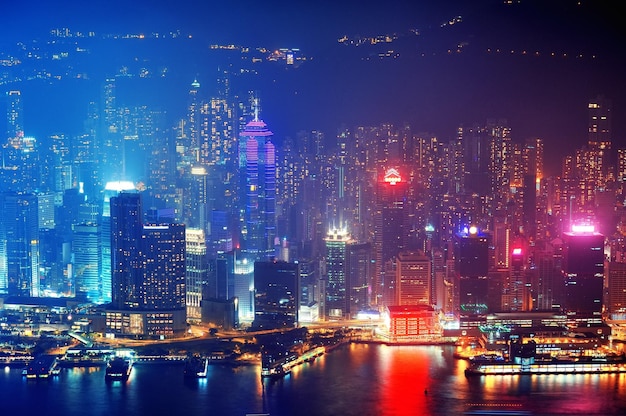 Victoria Harbor aerial view with Hong Kong skyline and urban skyscrapers at night.