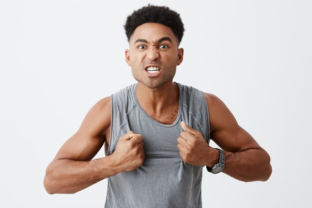 VIctory spirit is strong. Close up portrait of professional dark-skinned fighter with afro hairstyle ready to throw up hs shirt to scare his opponent. Sport and lifestyle concept