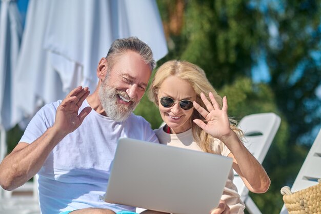 Video call. Mature couple having a video call and waving their hands