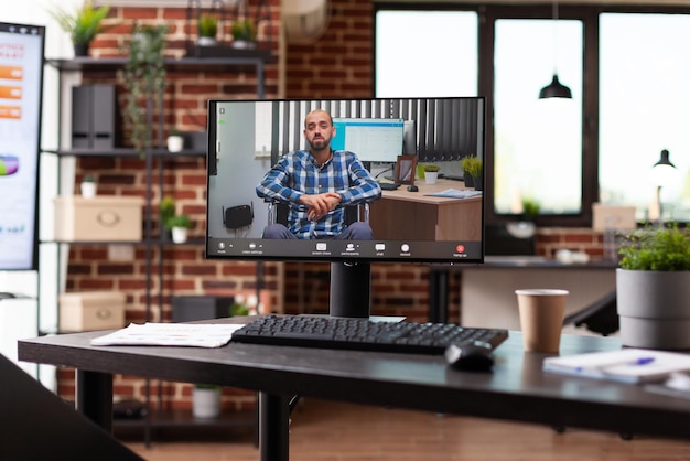 Video call meeting with business man on computer in office. Nobody in startup space with remote video conference and online teleconference on monitor for conversation with colleague.