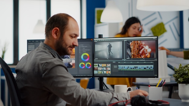 クリエイティブなスタートアップエージェンシーオフィスで働くポストプロダクションソフトウェアを使用して映画を編集するビデオメーカー...