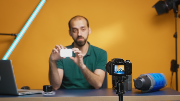 Видеооператор держит мини-светодиодную лампу во время записи обзора для видеоблога. Профессиональное студийное видео и фотооборудование для работы, звезда социальных сетей и влиятельный человек в фотостудии