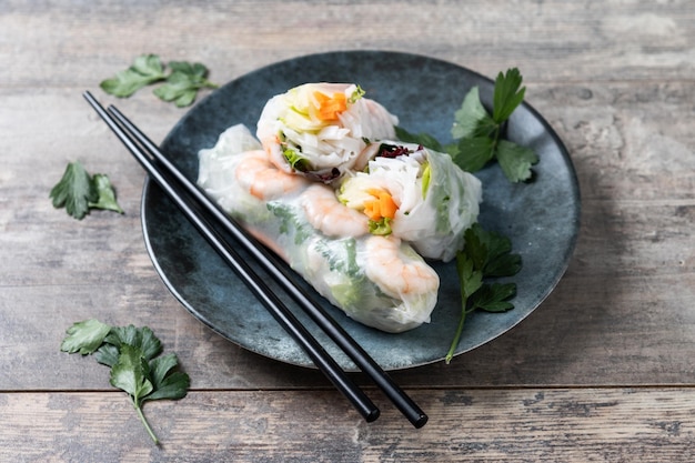 Foto gratuita rotoli di primavera vietnamiti con verdure, noodles di riso e gamberi su un tavolo di legno