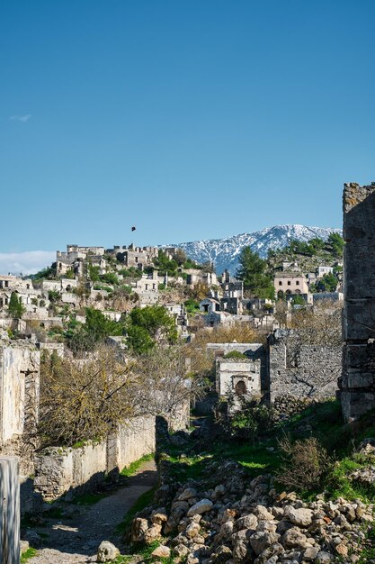 View of an abandoned city near Kayakoy village and snowcapped mountains Abandoned ghost town Karmilisos in winter in Fethiye Turkey ruins of stone houses Site of the ancient Greek city