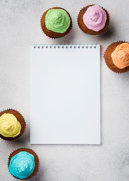 Above view arrangement with glazed muffins and notebook