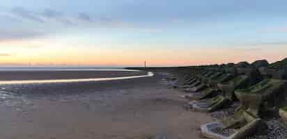 Foto gratuita vista della spiaggia di liverpool al tramonto, filari di frangiflutti, regno unito