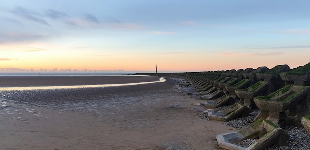 View of the beach in Liverpool at sunset, rows of breakwaters, United Kingdom