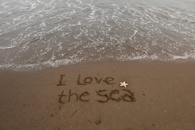 Foto gratuita vista della sabbia della spiaggia in estate con un messaggio scritto su di essa