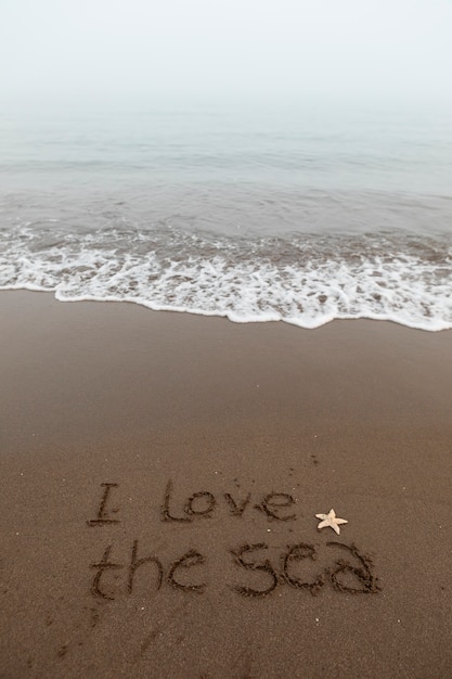 Foto gratuita vista della sabbia della spiaggia in estate con un messaggio scritto su di essa