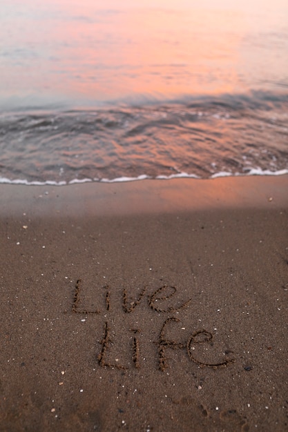 Foto gratuita vista della sabbia della spiaggia in estate con un messaggio scritto su di essa