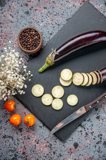 Free photo above view black eggplants sliced and whole on cutting board blue background