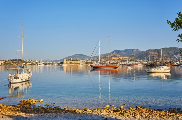 Вид на пляж Бодрум Эгейское море традиционные белые дома цветы пристань для яхт парусные лодки