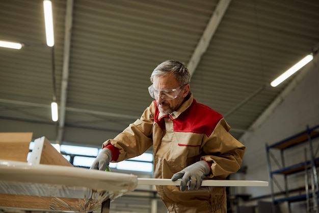 Below view of carpenter checking measurements while making furniture in a workshop