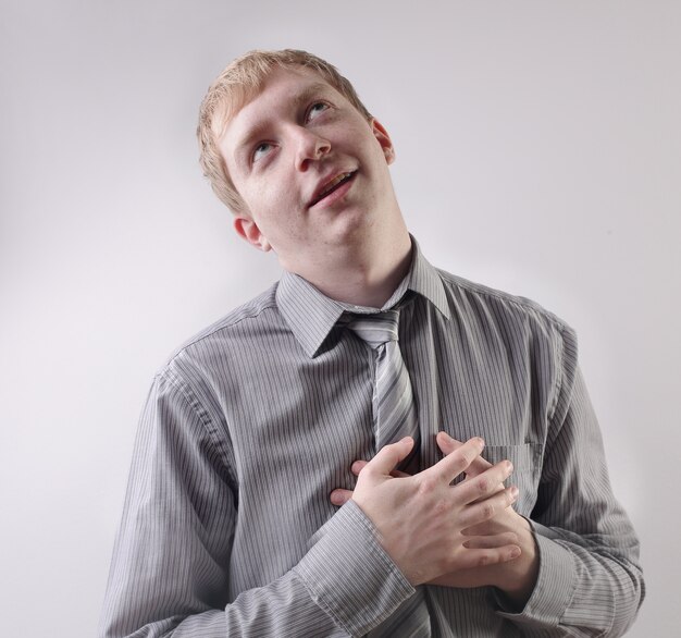 View of a caucasian male wearing a grey shirt with his hands on his chest