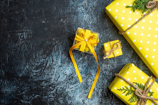 Above view of Christmas background with yellow gift boxes for family members on dark background
