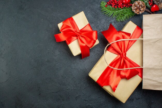 Above view of Christmas mood with beautiful gifts and fir branches conifer cone on dark background