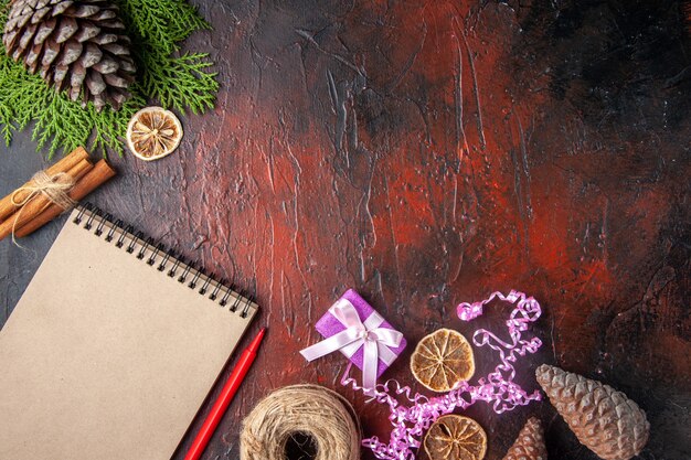 Above view of closed notebook with pen cinnamon limes and a ball of rope on dark background