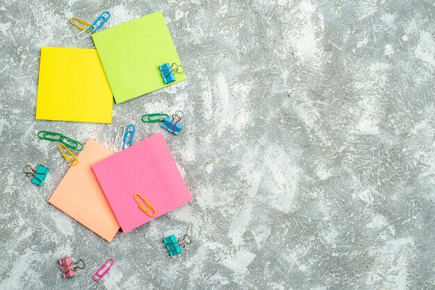 Above view of colorful note papers and other office appliances on gray background