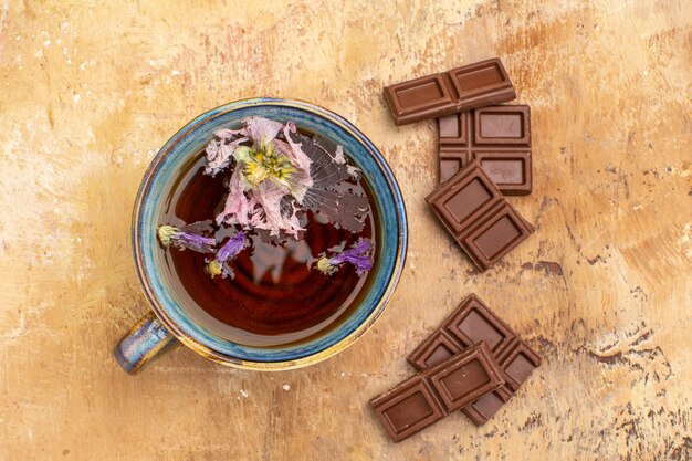 Above view of a cup of hot herbal tea and chocolate bars on mixed color table