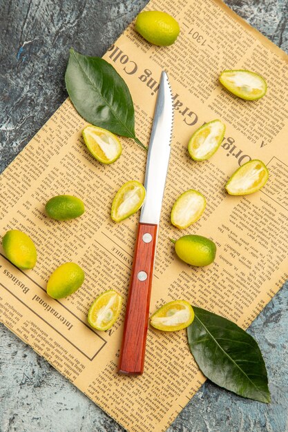 Above view of cut in half fresh kumquats on newspapers on gray background