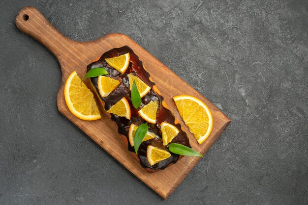黒いテーブルのまな板にオレンジとチョコレートで飾られたおいしいケーキのビューの上