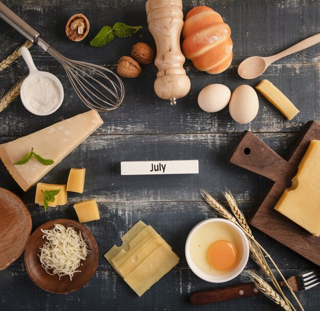 View of a delicious cheese platter with walnuts, eggs, and flour on the table with "JULY" word