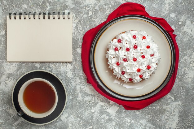 빨간 수건에 과일과 얼음 배경에 노트북 옆에 홍차 한잔으로 장식 된 맛있는 크림 케이크의 위보기