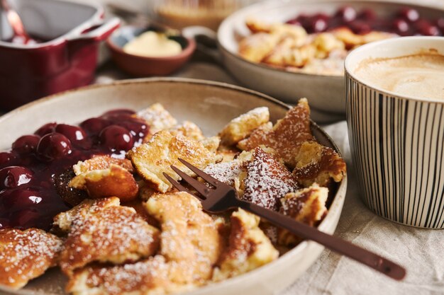 A view of delicious fluffy pancakes with cherry and powdered sugar