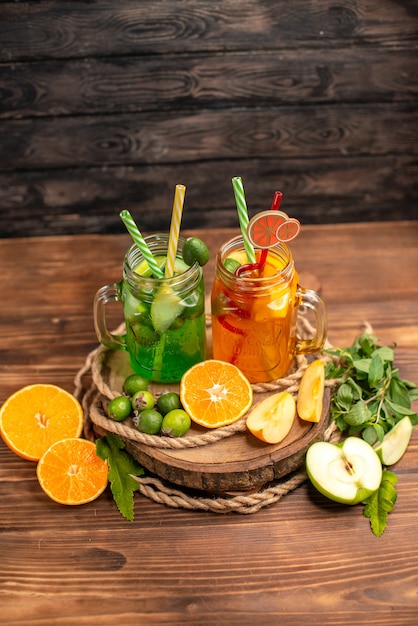 Above view of delicious fresh juices and fruits on a wooden tray on a brown background