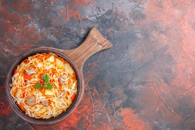 Above view of delicious noodle soup with chicken on wooden cutting board on dark background