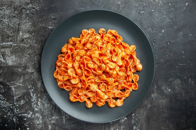 Above view of delicious pasta meal on a black plate for dinner on dark background